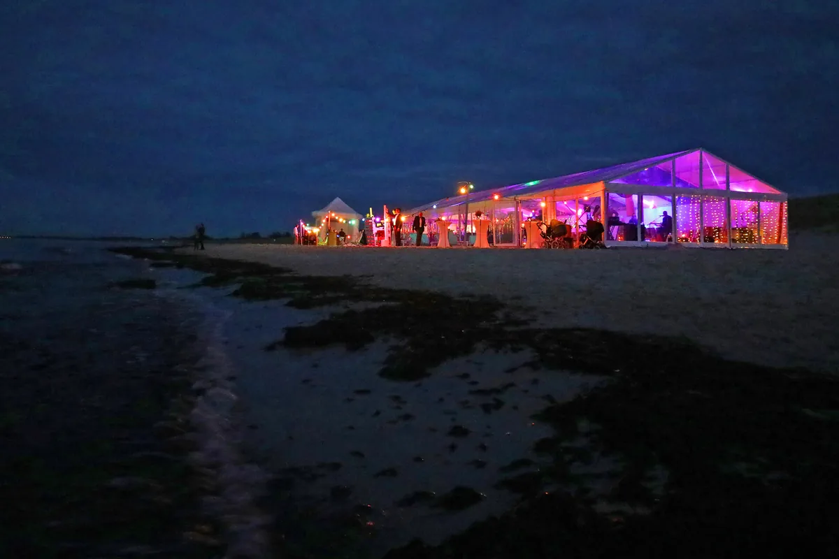 Beleuchtetes Glaszelt direkt am Ostseestrand am Abend